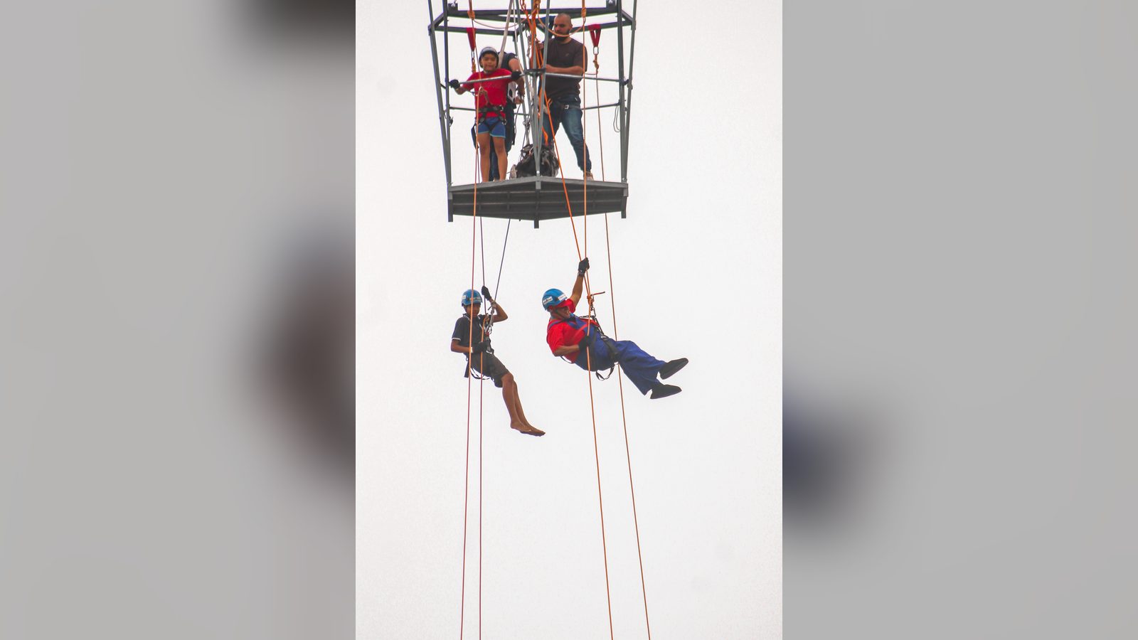 Crianças descendo de rapel a partir do cesto do guindaste